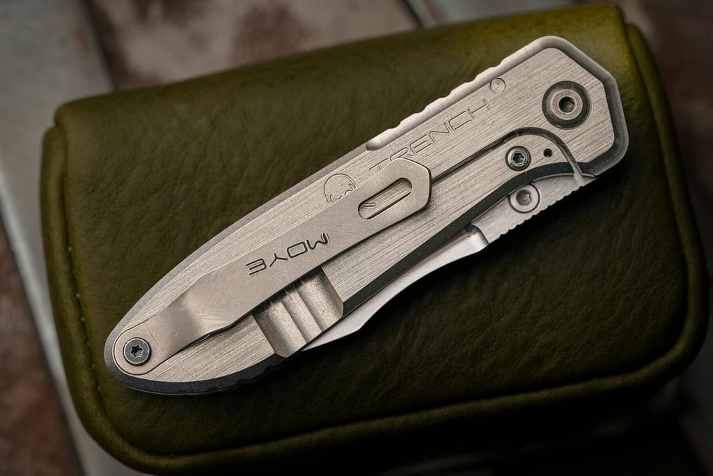 Detailed shot of a folding knife with engraved branding on a textured leather case.