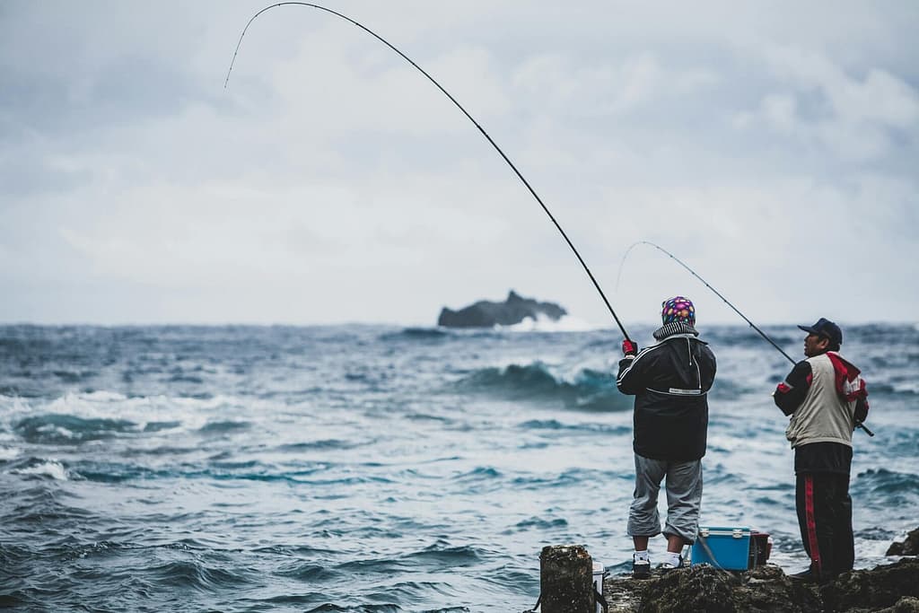 Two men fishing by the sea in Taiwan, capturing the essence of patience and recreation.