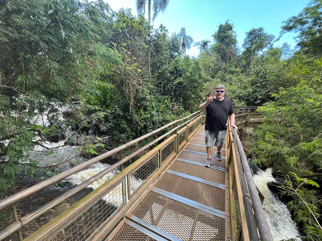 Man walking across a metal bridge over Salto Chico waterfall