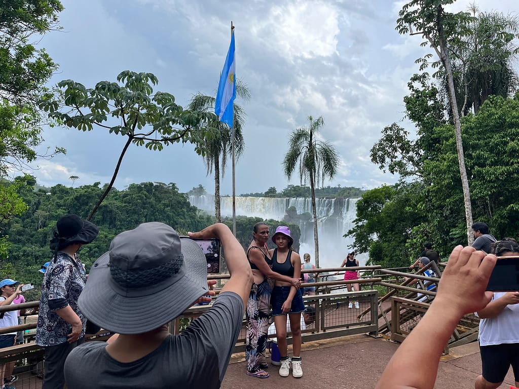 Tourists taking photos of Iguazu Falls under an Argentina flag