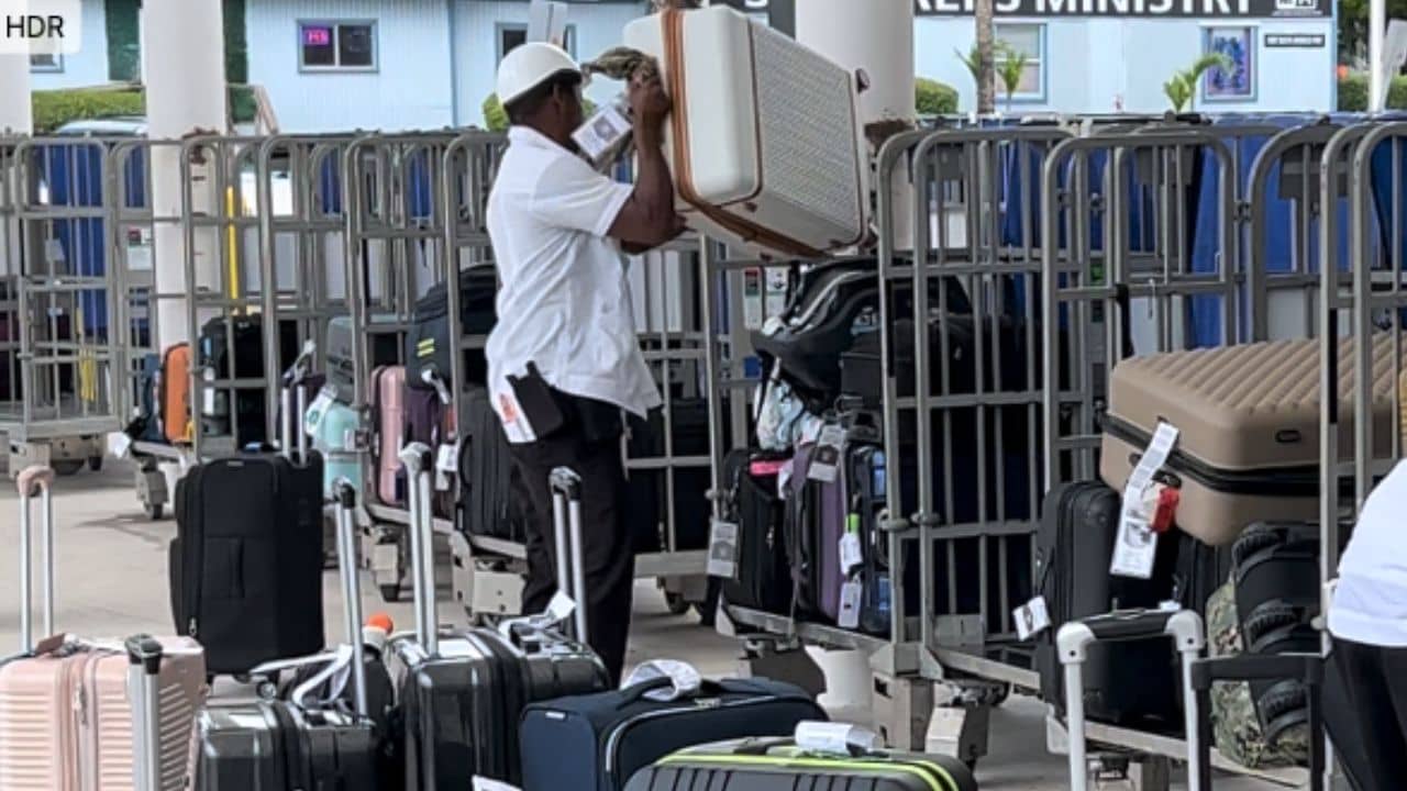 Man loading a suitcase onto a cart in a cruise terminal