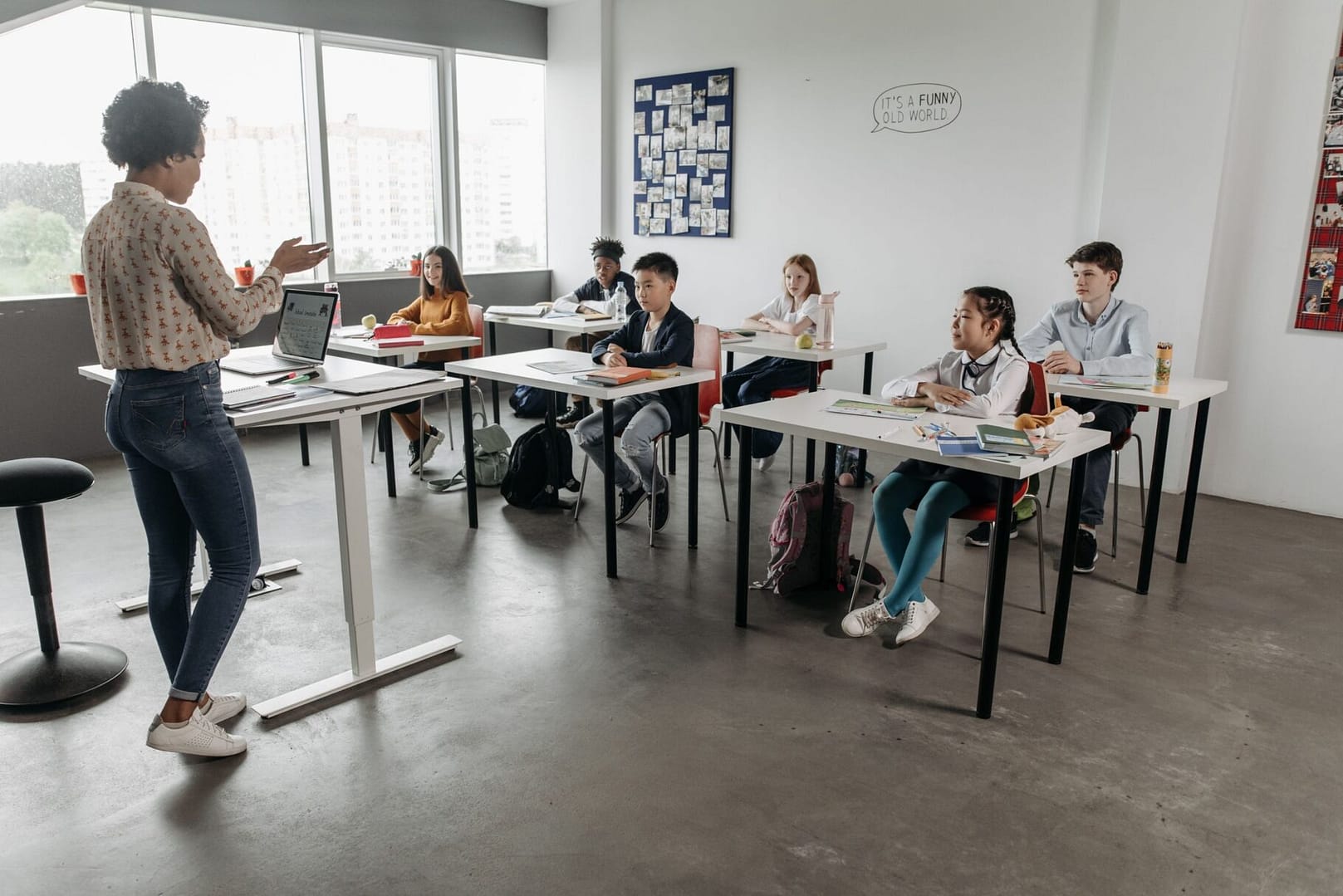 Teacher interacting with students in a modern classroom, fostering a diverse and engaging educational environment.