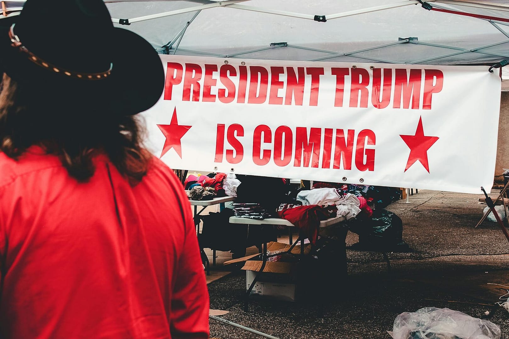 Banner promoting a political event for Donald Trump in Wheeling, WV with market stalls.
