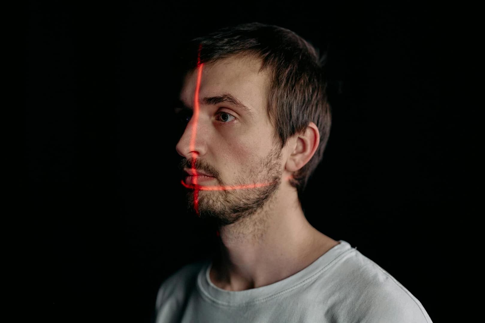 A man undergoes a facial recognition scan with a laser grid in a studio setting.