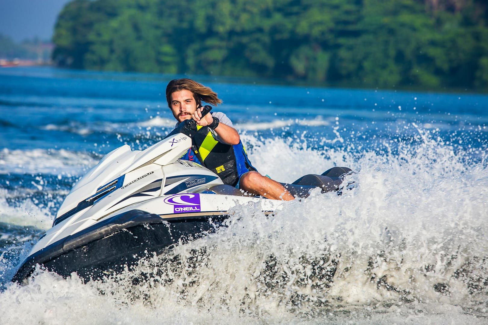 man in safety vest riding a personal watercraft during daytime