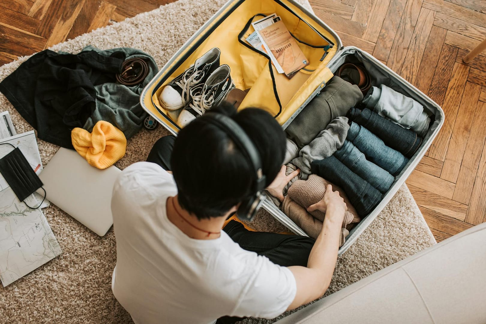 a man listening on his headphones while packing his clothes