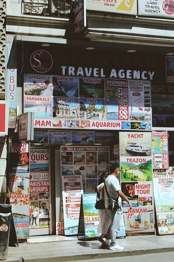 a man walking down a street with a travel agency sign