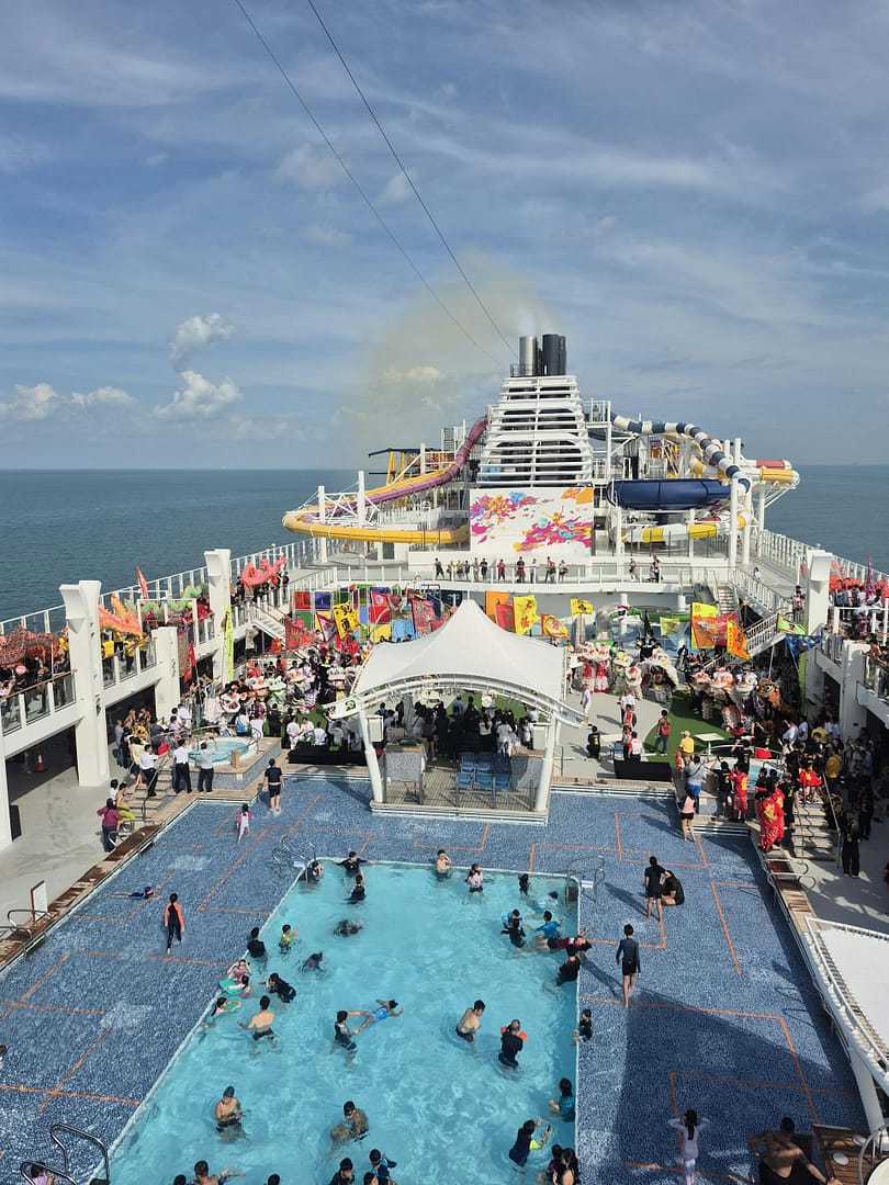A lively cruise ship deck with a bustling pool area and ocean views, perfect for vacations.
