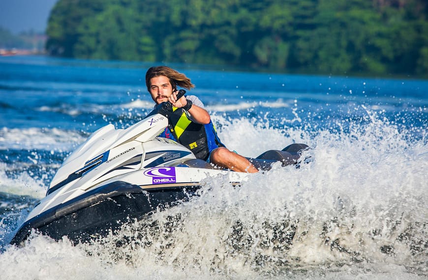 man in safety vest riding a personal watercraft during daytime