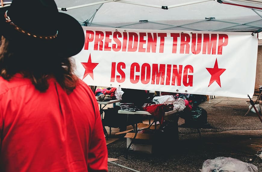 Banner promoting a political event for Donald Trump in Wheeling, WV with market stalls.
