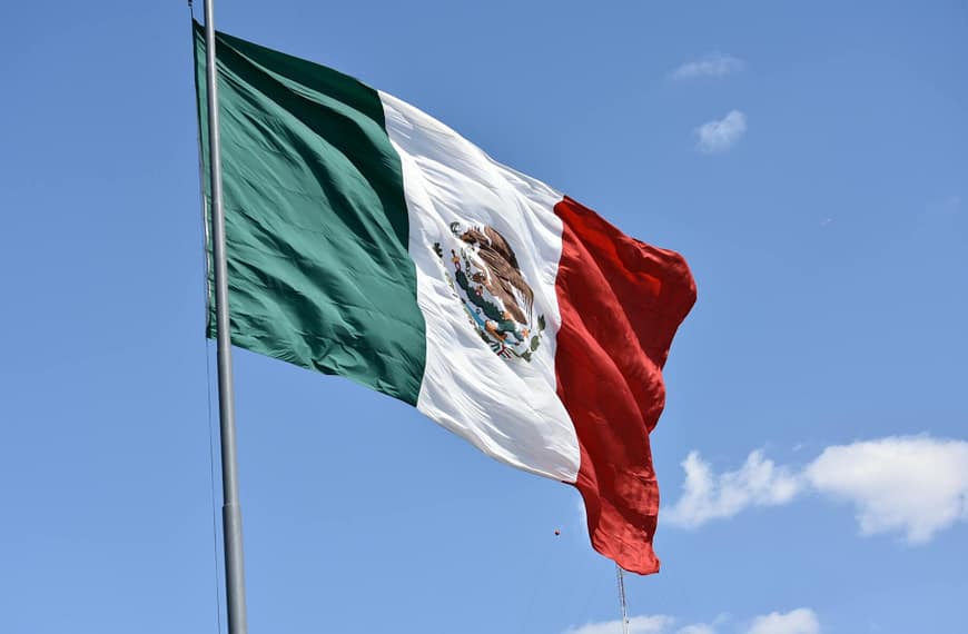 Vibrant Mexican flag waving proudly against a clear blue sky in Ciudad de México.