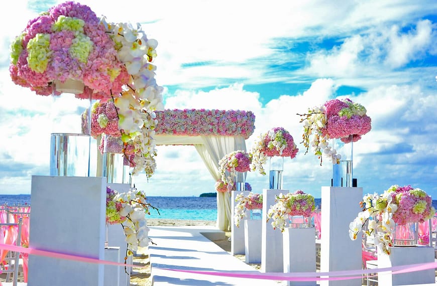 Beautifully decorated beach wedding setup with vibrant flower arrangements by the sea.