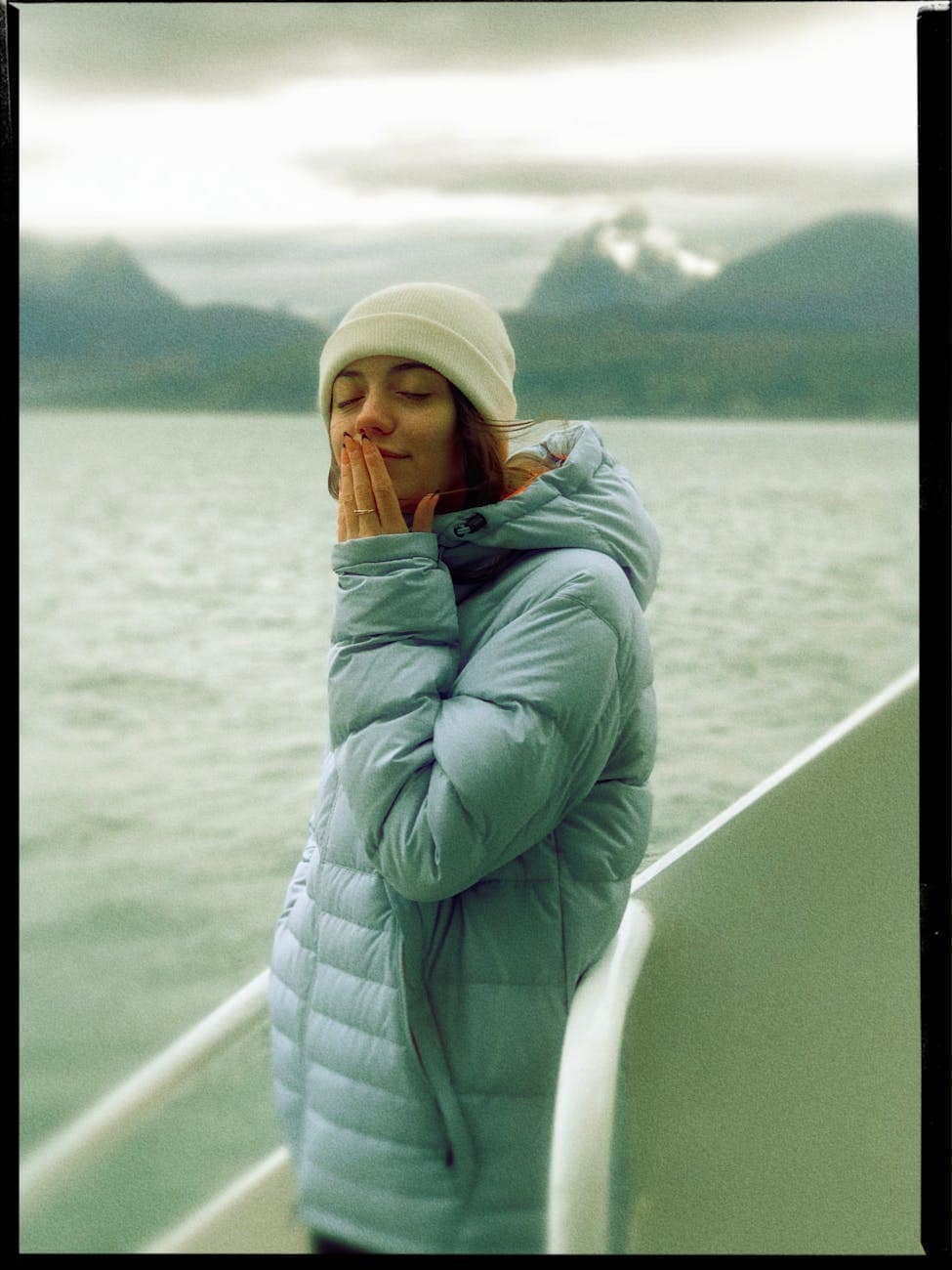 woman in blue jacket and white beanie while eyes closed