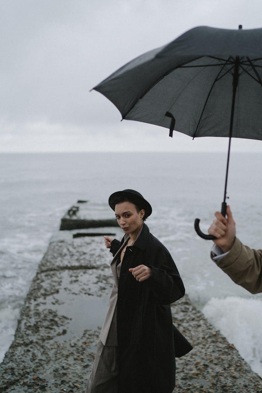 woman wearing black coat walking on concrete jetty
