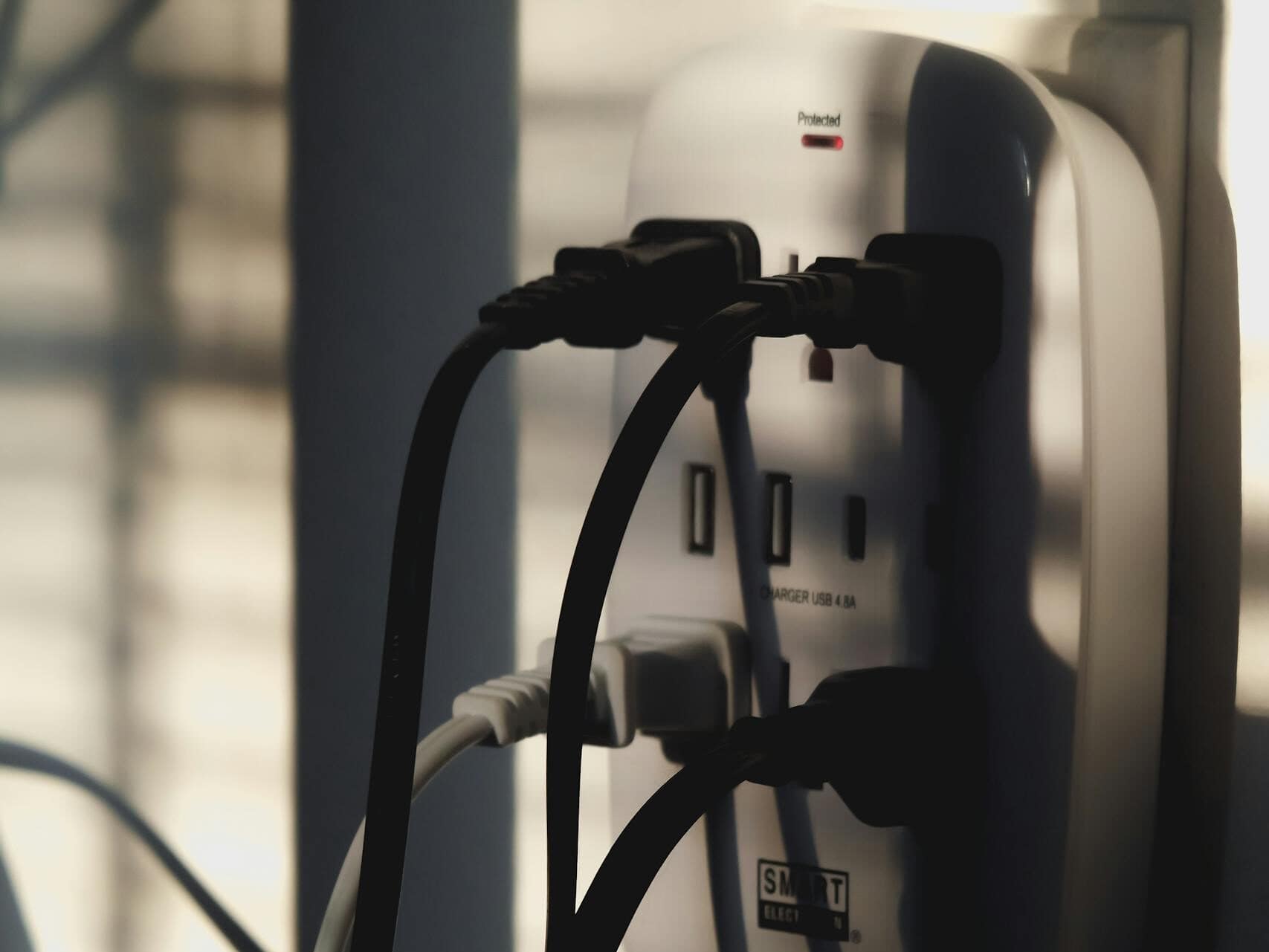 Multiple charging cables plugged into a wall outlet, showcasing energy connectivity.